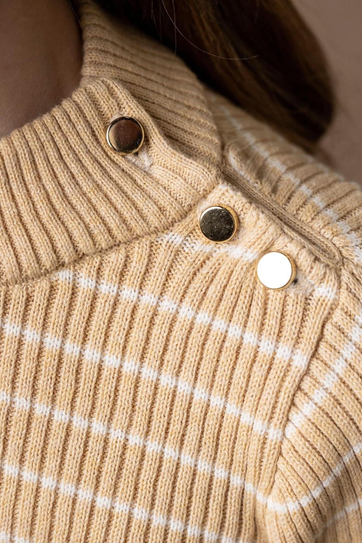 Close-up of a cozy, oatmeal heather striped mock neck sweater featuring rib knit texture and stylish button details. Made from 100% organic cotton, its perfect for kids.