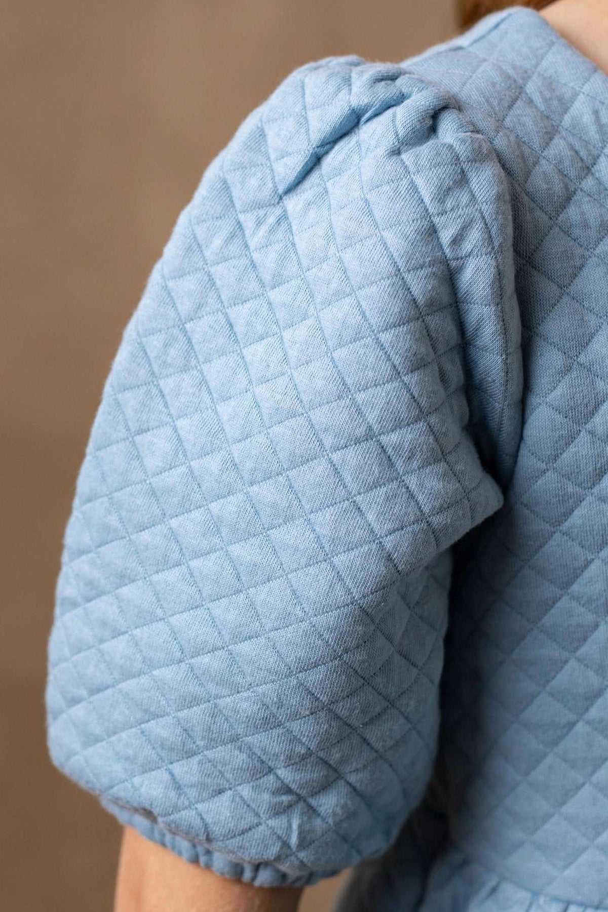 Close-up of a light dusty blue quilted puff sleeve, showcasing the soft texture and organic cotton material ideal for kids.