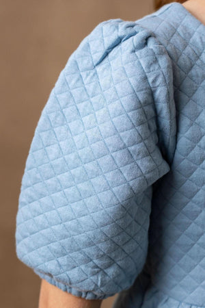 Close-up of a light dusty blue quilted puff sleeve, showcasing the soft texture and organic cotton material ideal for kids.