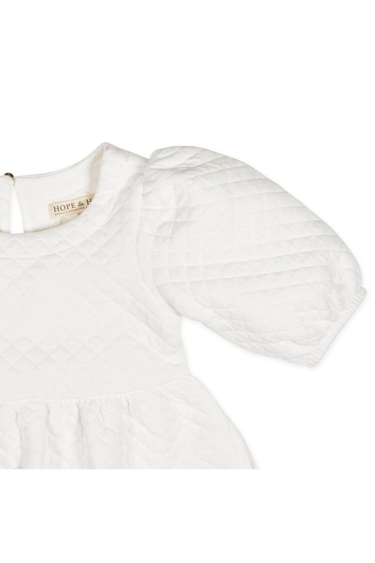 Close-up of a soft white quilted dress featuring puff sleeves and a keyhole back, labeled Hope & Henry.