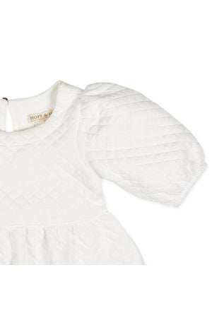 Close-up of a soft white quilted dress featuring puff sleeves and a keyhole back, labeled Hope & Henry.
