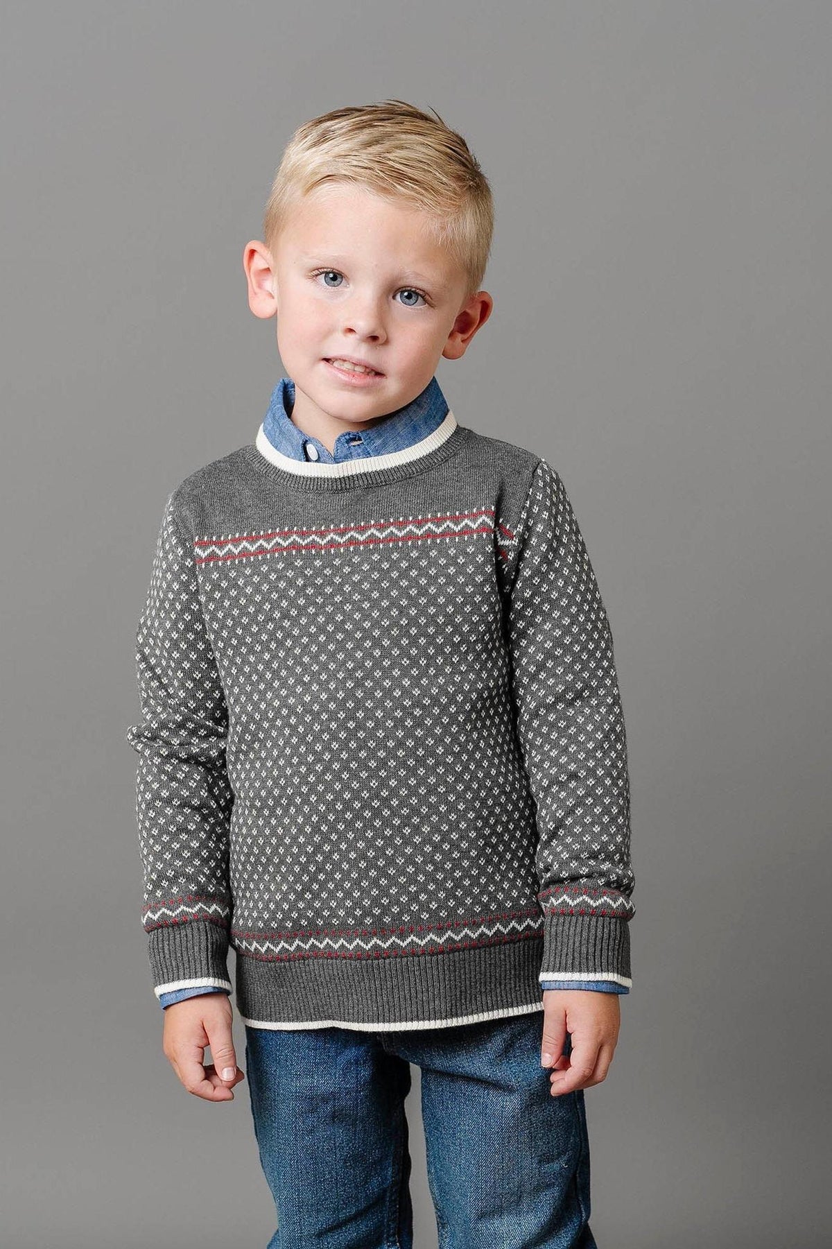 A young boy is wearing a charcoal crew neck sweater with an ivory birdseye pattern, paired with a blue collared.