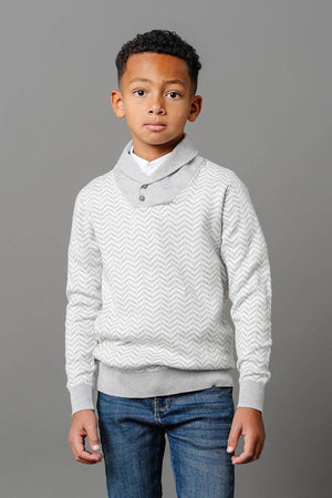 A young boy models a grey herringbone knit sweater with a shawl collar and buttons, paired with blue jeans.