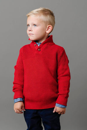 A young boy wears a vibrant red mock neck sweater with textured stitching and a button placket. The sweater is made from soft organic cotton, perfect for stylish, sustainable dressing.