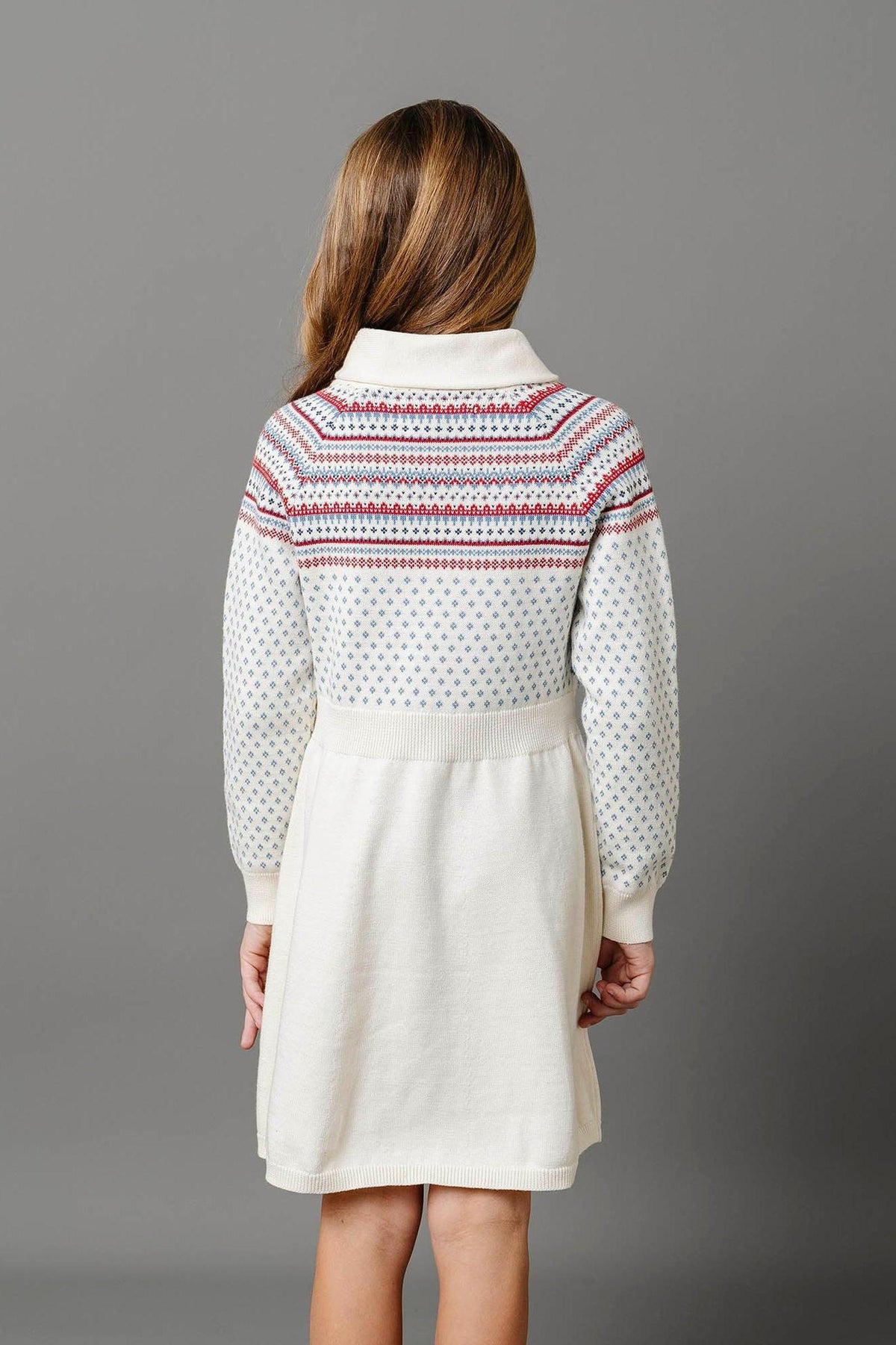 Back view of a cream sweater dress with a shawl collar, featuring a fair isle pattern in red and blue.