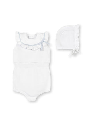 A white organic cotton romper features a ruffle collar with a blue bow, accompanied by a matching ruffle-edge bonnet.