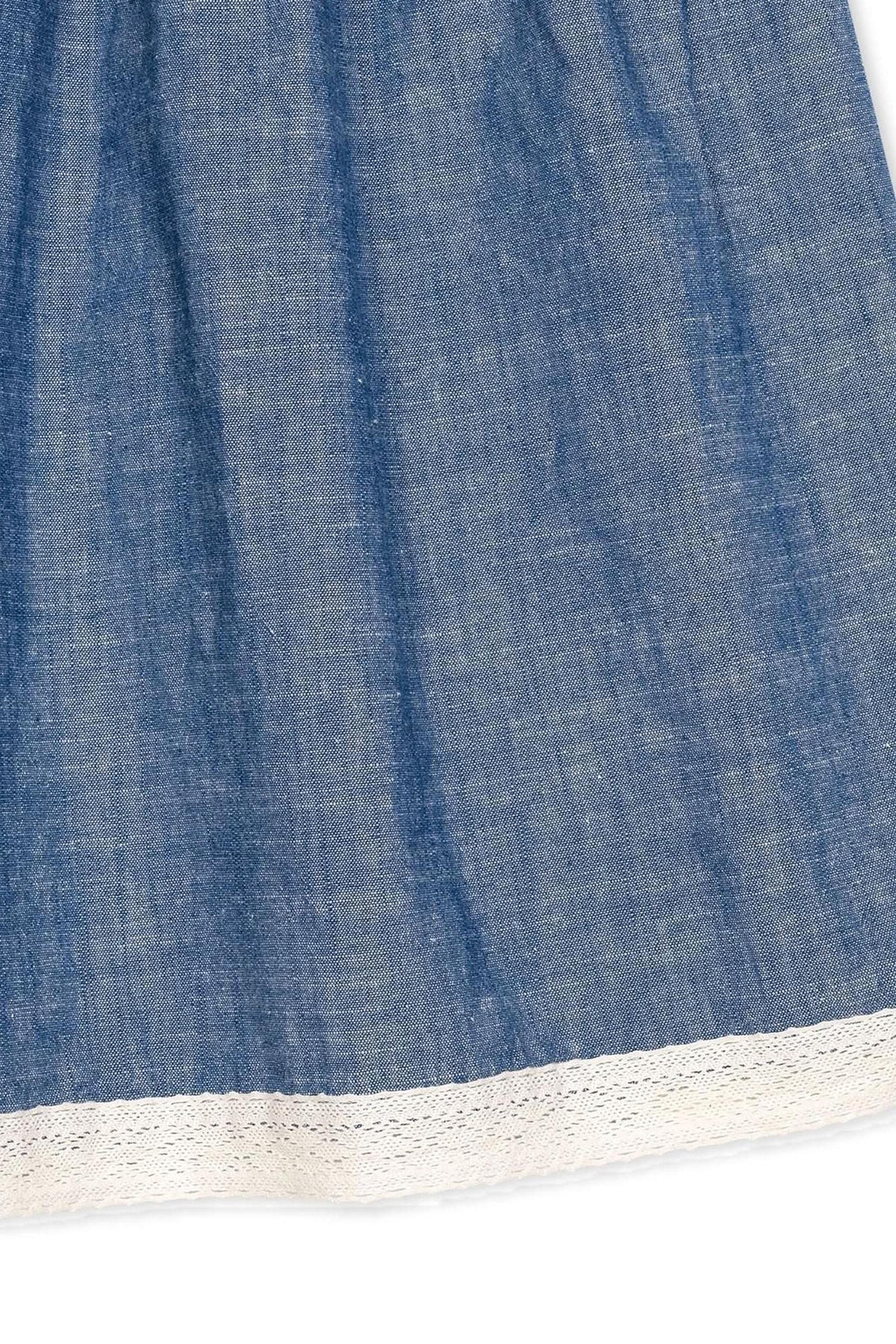 Close-up of a chambray dress featuring delicate white crochet trim along the hem, showcasing soft organic cotton fabric.