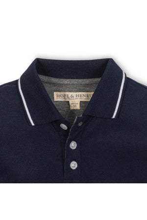 Close-up view of a navy blue Hope & Henry organic cotton polo featuring a pointed collar with white tipping and a front button placket.