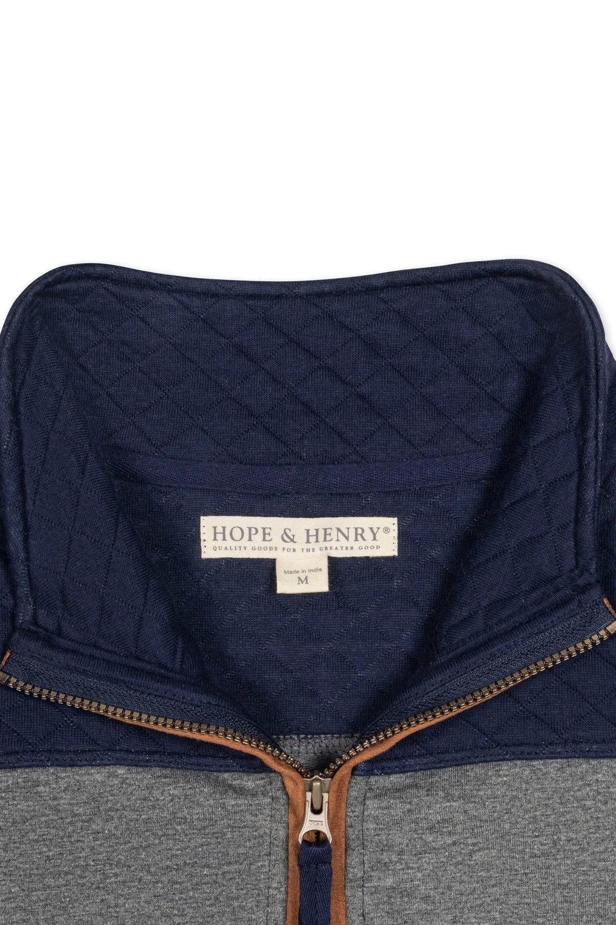 Close-up view of a Hope & Henry organic cotton pullover featuring a navy mock neck and half zip, with a diamond quilted pattern around the yoke and faux suede piping.