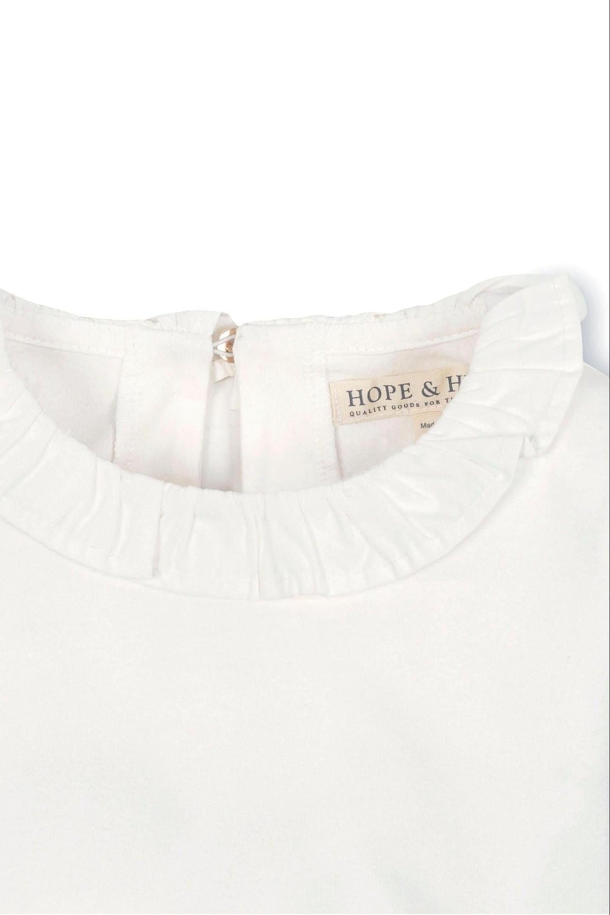 Close-up of a white organic cotton top featuring a ruffle collar and a back keyhole closure, labeled Hope & Henry.