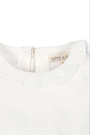 Close-up of a white organic cotton top featuring a ruffle collar and a back keyhole closure, labeled Hope & Henry.