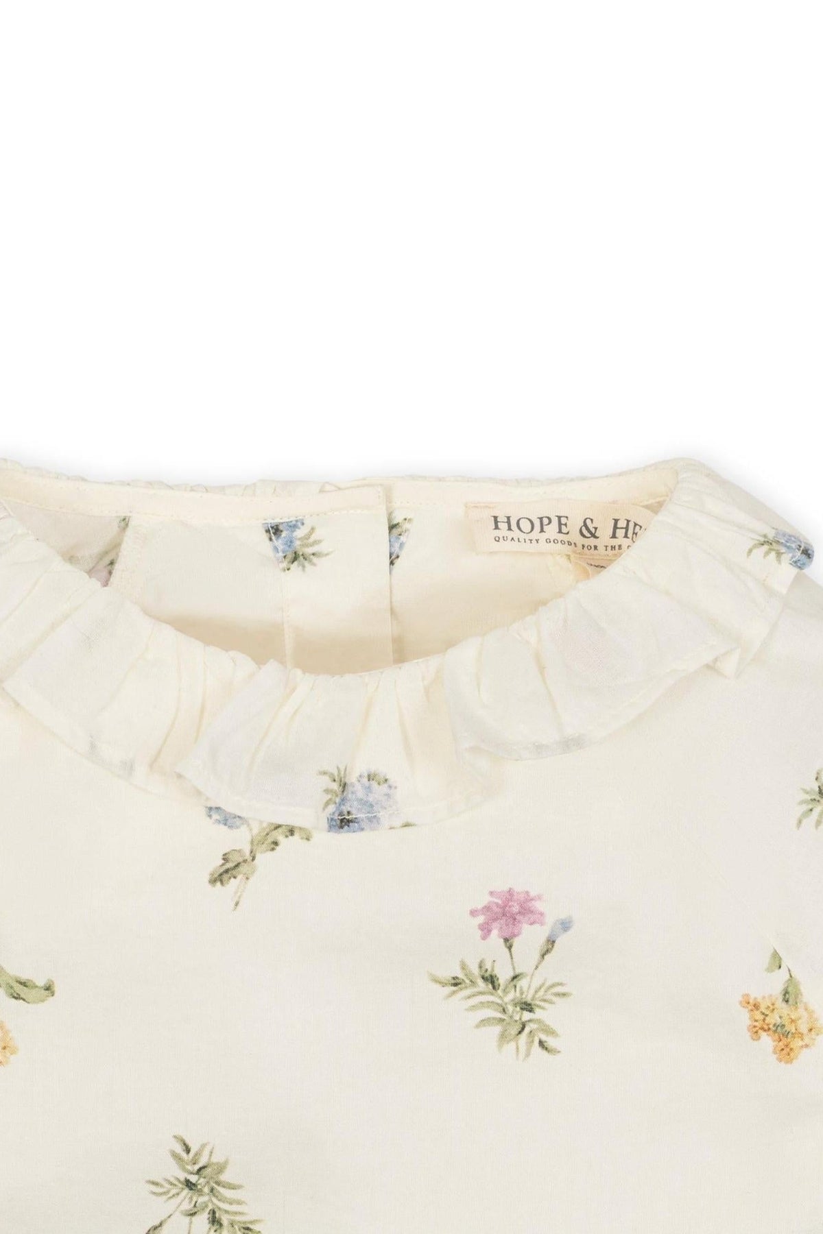 Close-up of an ivory floral top featuring a ruffle collar, made from soft organic cotton with delicate flower prints.