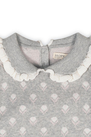 Close-up of a gray sweater featuring a Peter Pan collar with ruffle edges and floral intarsia design, labeled HOPE.