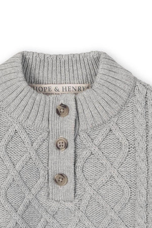 Close-up of a light grey sweater featuring a mock neck, textured knit pattern, and button placket, labeled Hope & Henry.