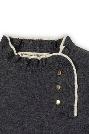 Close-up of a charcoal gray sweater dress featuring a ruffled collar and gold buttons, made from organic cotton.
