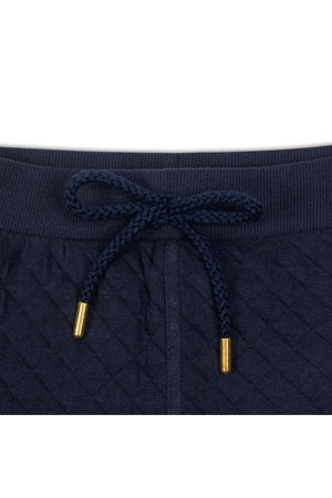 Close-up of a navy quilted waistband featuring a braided drawcord with gold metal tips, showcasing soft organic cotton material.