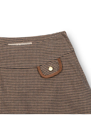 Close-up of a brown houndstooth patterned fabric featuring a decorative flap pocket with a gold button, designed for childrens wear.