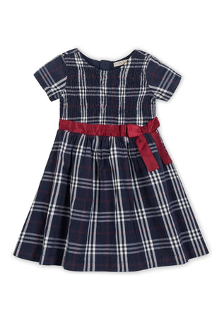 Navy plaid dress with short sleeves, smocked bodice, and a red ribbon belt, made from organic cotton. Ideal for girls.