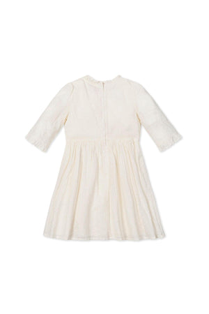 Ivory eyelet dress with elbow-length sleeves and ruffle details, featuring a back zipper; made from organic cotton.