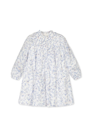 White dress featuring a delicate blue floral print and smocked yoke, designed for girls in soft, breathable organic cotton.