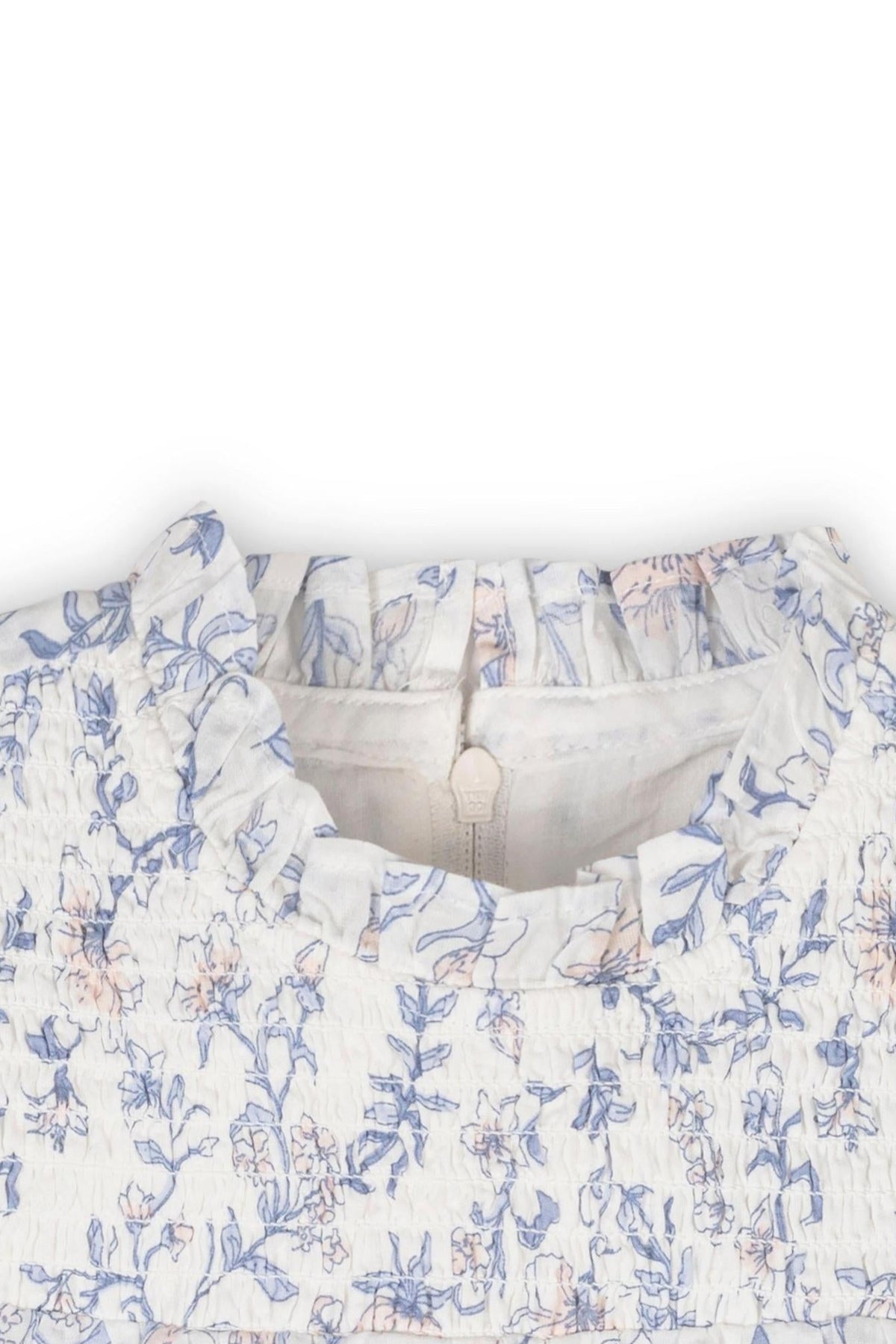 Close-up of a white dress featuring a gray and pink floral print, with a smocked yoke and ruffled neckline.