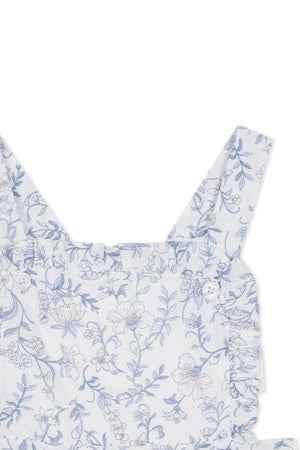 Close-up of a blue floral pattern on an organic cotton apron dress featuring delicate ruffles and adjustable straps, designed for toddlers and kids by Hope & Henry.