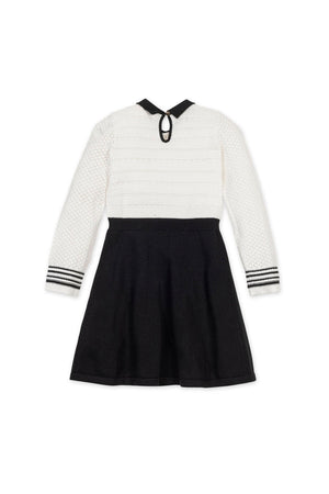 A back view of a Hope & Henry sweater dress showcasing a white textured bodice, black skirt, and striped sleeve details.