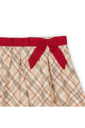 Close-up of a plaid skirt in cream and red, featuring a red waist sash with a bow.