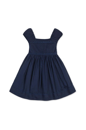 Navy organic cotton dress with puff sleeves and pintuck detailing, featuring a flared skirt and embroidered hem.