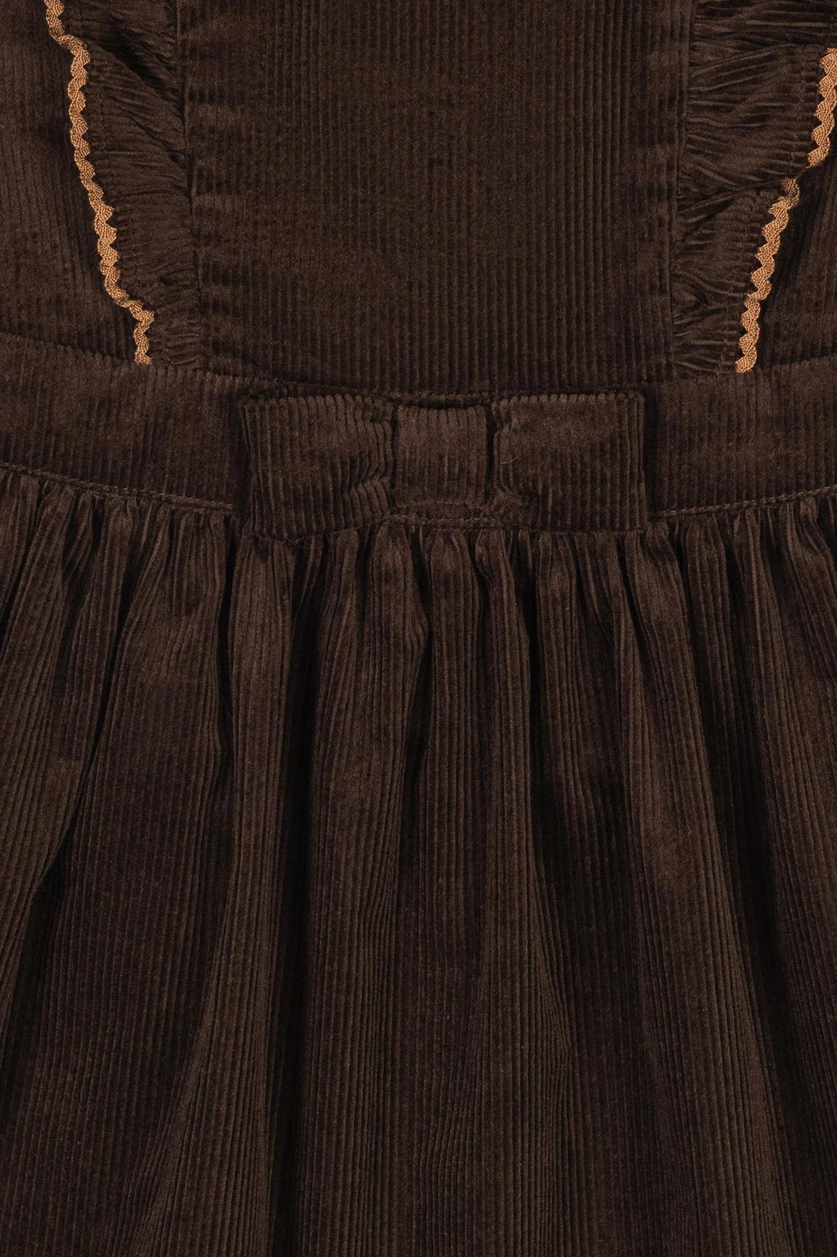 Close-up of a brown organic cotton corduroy jumper dress featuring ruffled details and a gathered skirt.
