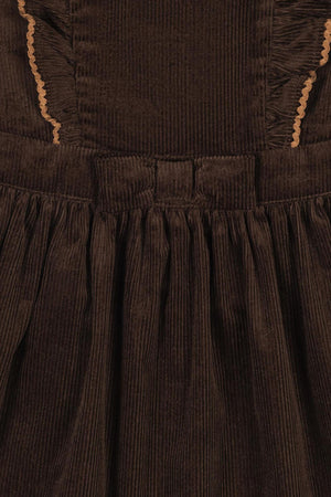 Close-up of a brown organic cotton corduroy jumper dress featuring ruffled details and a gathered skirt.