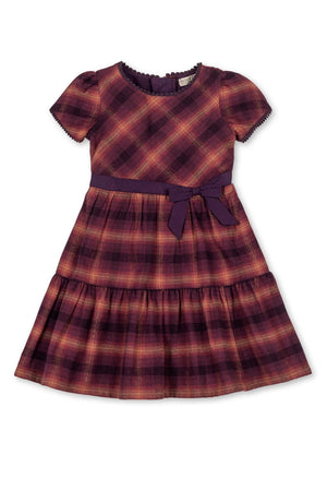 A tiered flannel dress in sugar plum plaid, featuring puff sleeves and a coordinating waist tie. Made from organic cotton.