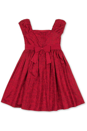 A vibrant fireside red toile dress features delicate puff sleeves and a tailored bodice. Designed for girls, it includes a coordinating waist sash with a bow, crafted from organic cotton.