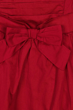 Close-up of a red dress featuring a bow at the waist, made from soft fabric with a ruched bodice.