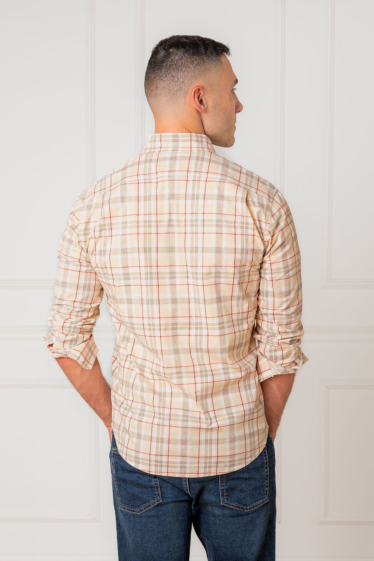 A man is seen from the back wearing a long-sleeve, fireside plaid shirt made of soft organic cotton.