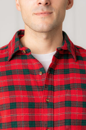 A close-up of a man wearing a red and green plaid flannel shirt with a button-down collar. The fabric appears soft and cozy, suitable for casual wear or family gatherings.