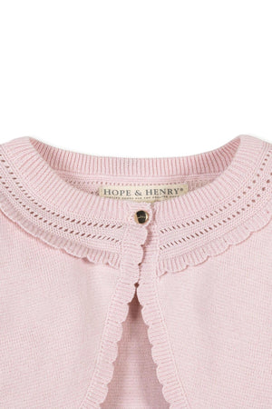 Close-up of a pink Hope & Henry organic cotton cropped cardigan featuring a delicate pointelle pattern and pearlized buttons.