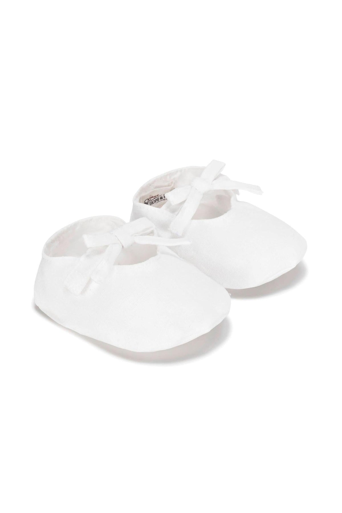 White linen baby shoes with a decorative bow and soft design, perfect for infants aged 0-12 months.