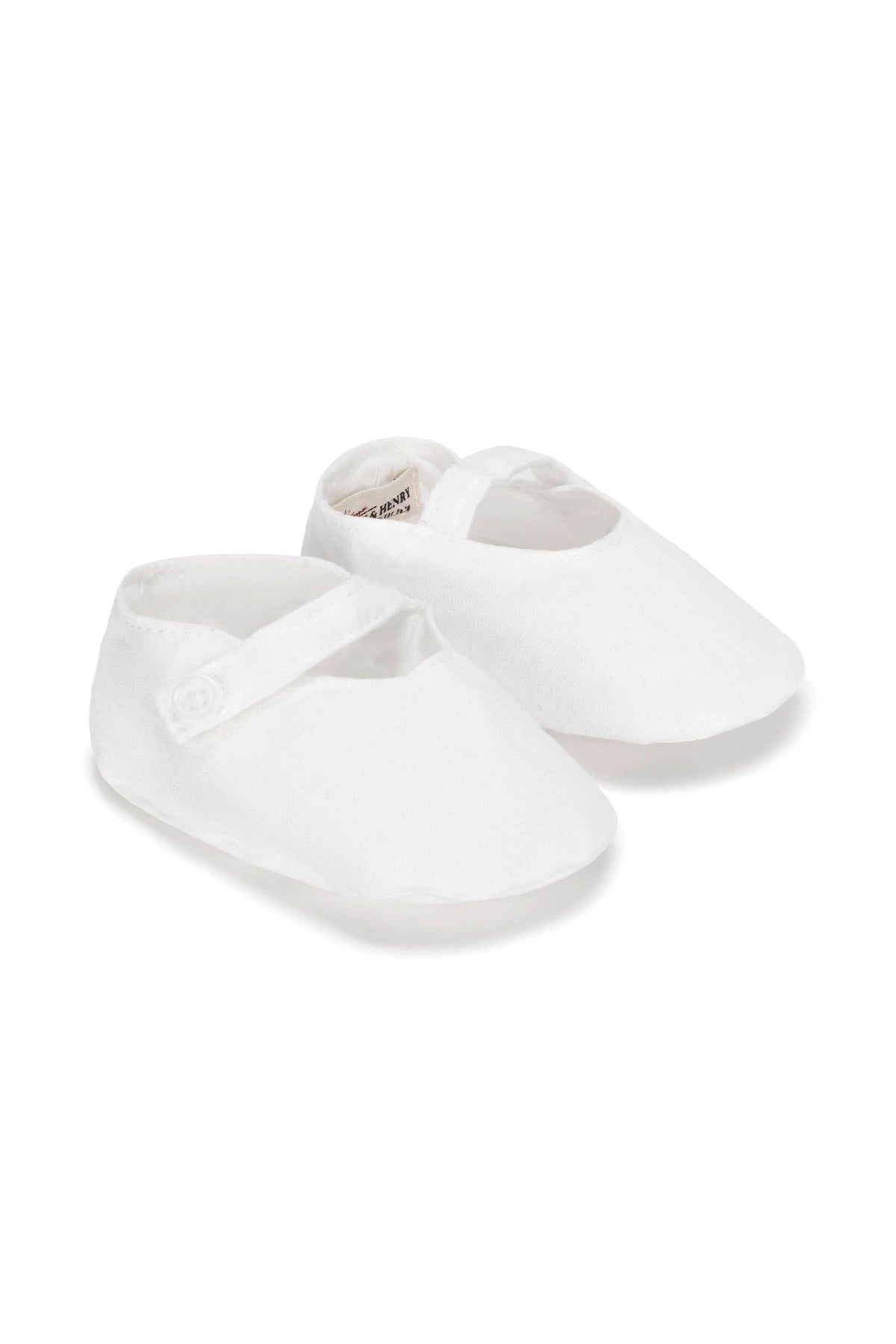 White linen baby shoes feature a button strap closure, perfect for infants up to 24 months. Ideal for various outfits.