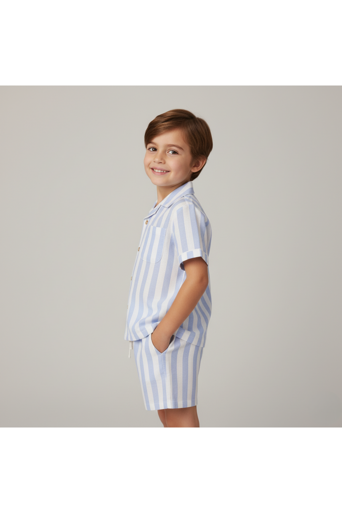 A smiling child wears a lightweight blue-striped shirt and shorts set made from organic cotton. The outfit is designed for comfort, perfect for summer adventures.