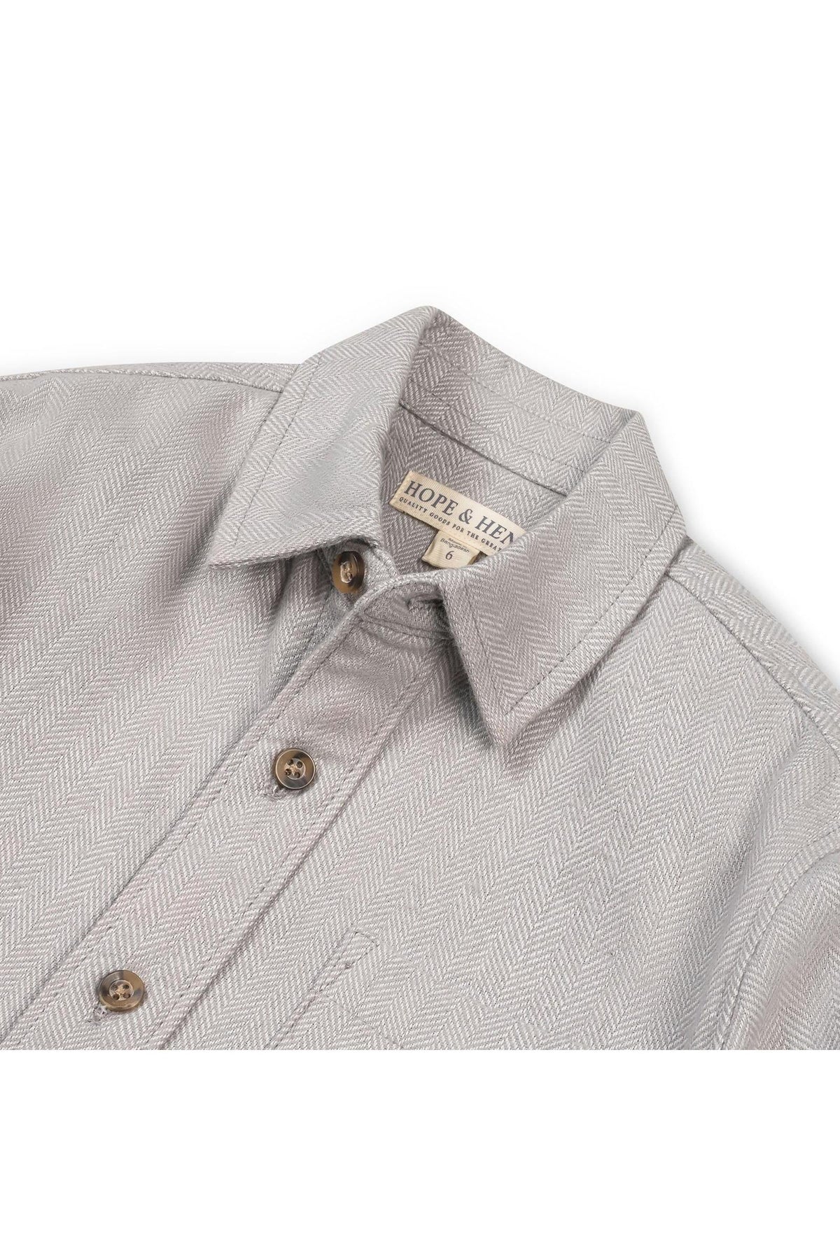 Close-up of a grey organic cotton flannel shirt featuring a herringbone pattern, button details, and a collar. The shirt is from Hope & Henry, designed for ages 2T to 18.