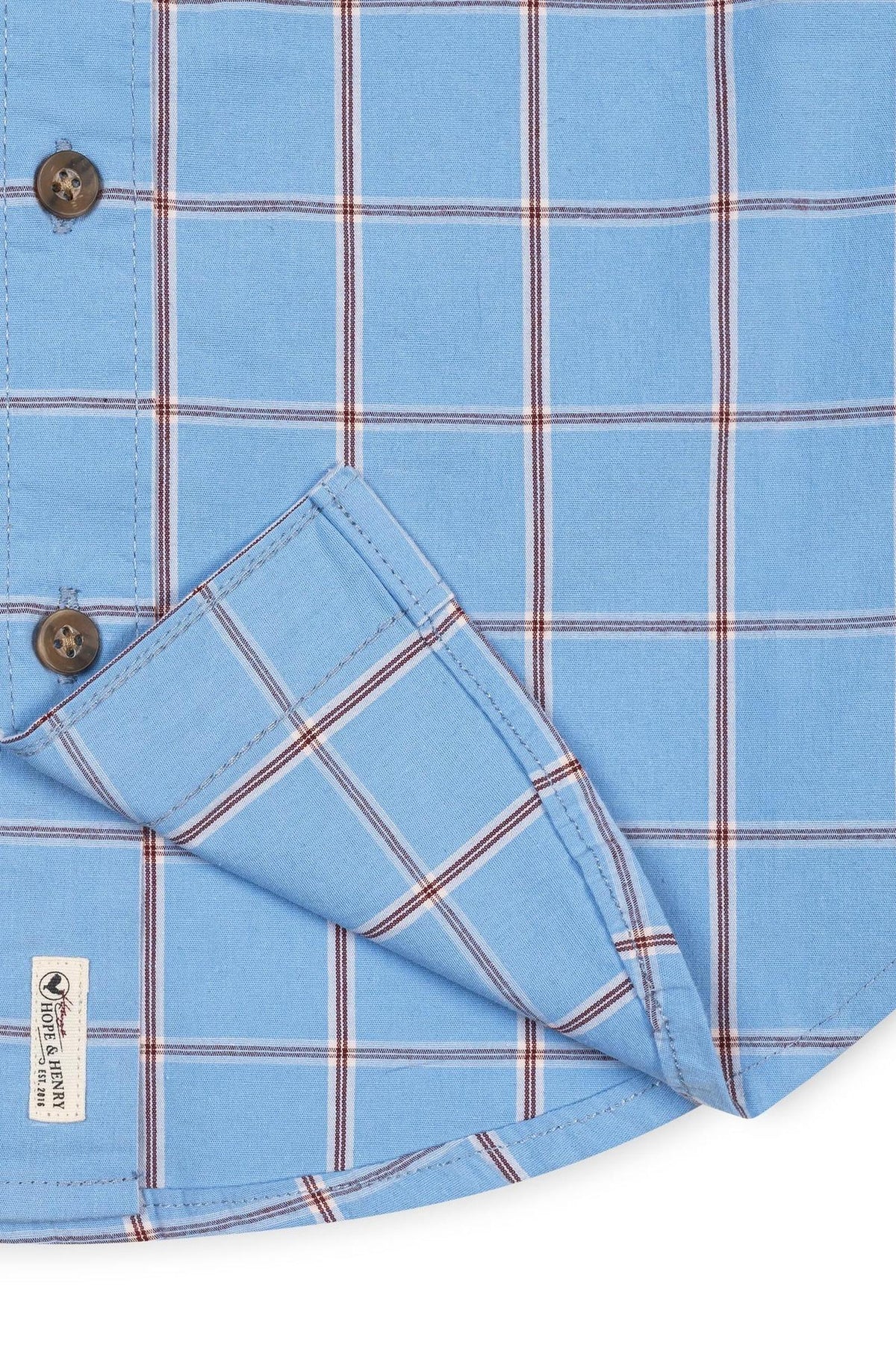 Close-up view of a blue plaid organic cotton shirt featuring a button-down collar and a functional chest pocket. The fabric has a soft texture, showcasing sustainable materials and classic styling.