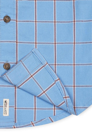 Close-up view of a blue plaid organic cotton shirt featuring a button-down collar and a functional chest pocket. The fabric has a soft texture, showcasing sustainable materials and classic styling.