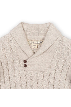 Light oatmeal shawl collar cable sweater made from soft organic cotton, featuring a button closure and intricate cable knit design.