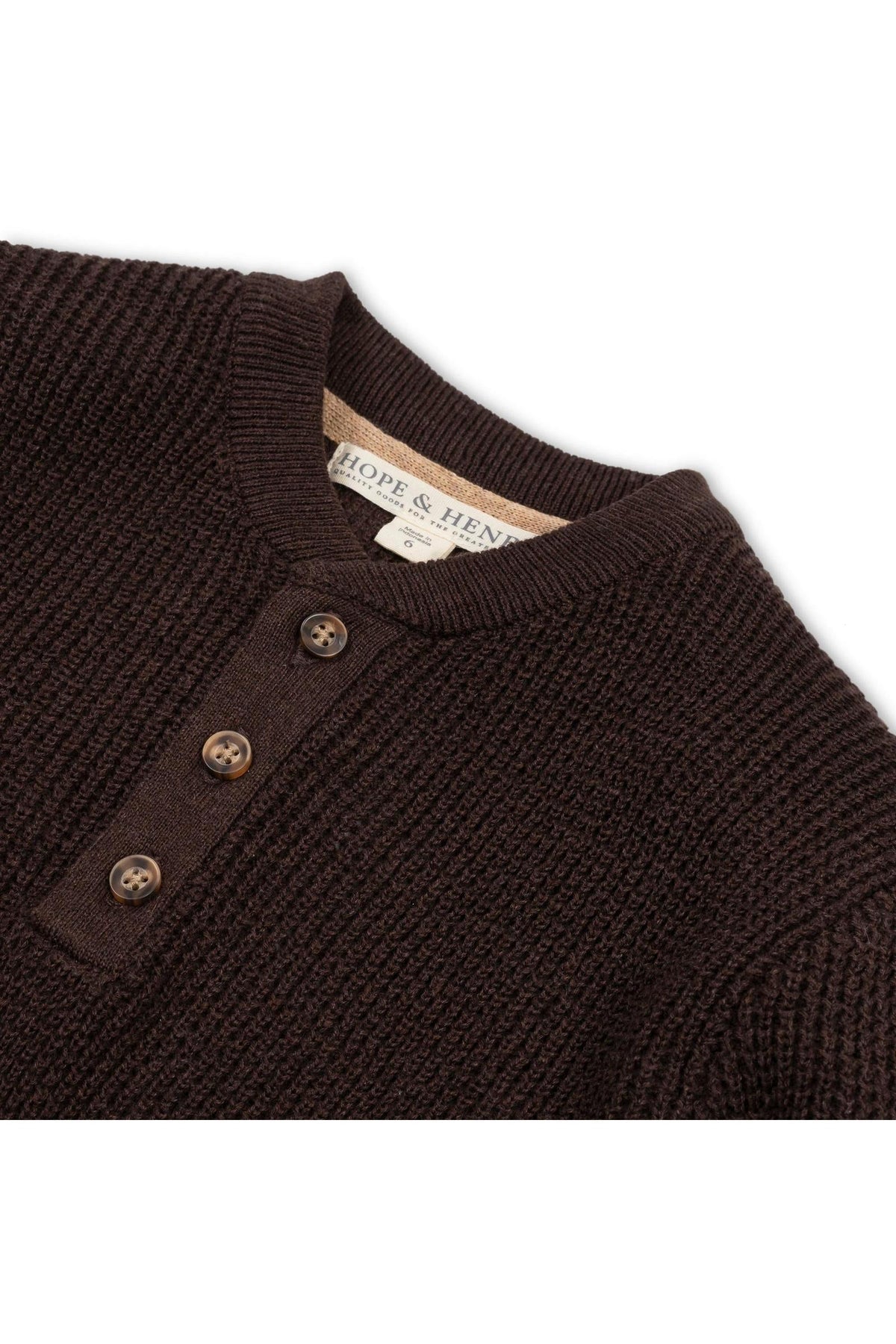 Close-up of a chocolate brown organic cotton sweater henley, featuring a textured knit, three wooden buttons, and a label that reads Hope & Hen, ideal for boys sizes 2T to.