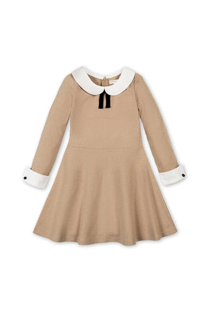 A tan organic cotton dress featuring a Peter Pan collar and white cuffs, adorned with a black velvet bow. Ideal for toddlers and girls, this piece combines style with comfort.