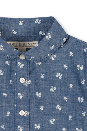 A close-up view of a chambray top featuring a Peter Pan collar, delicate floral patterns, and button details. Made from soft, sustainable organic cotton for toddlers and girls.