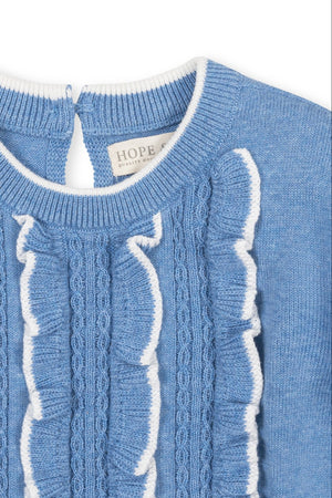Close-up of a medium blue sweater dress featuring a ruffled bodice and cable knit design, made from soft organic cotton. The dress has a keyhole closure at the back neck.