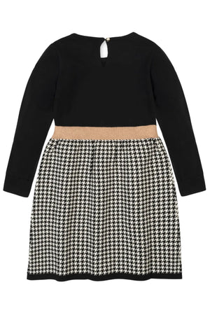 Back view of an organic cotton toddler skater sweater dress featuring a solid black bodice and a black houndstooth patterned skirt.