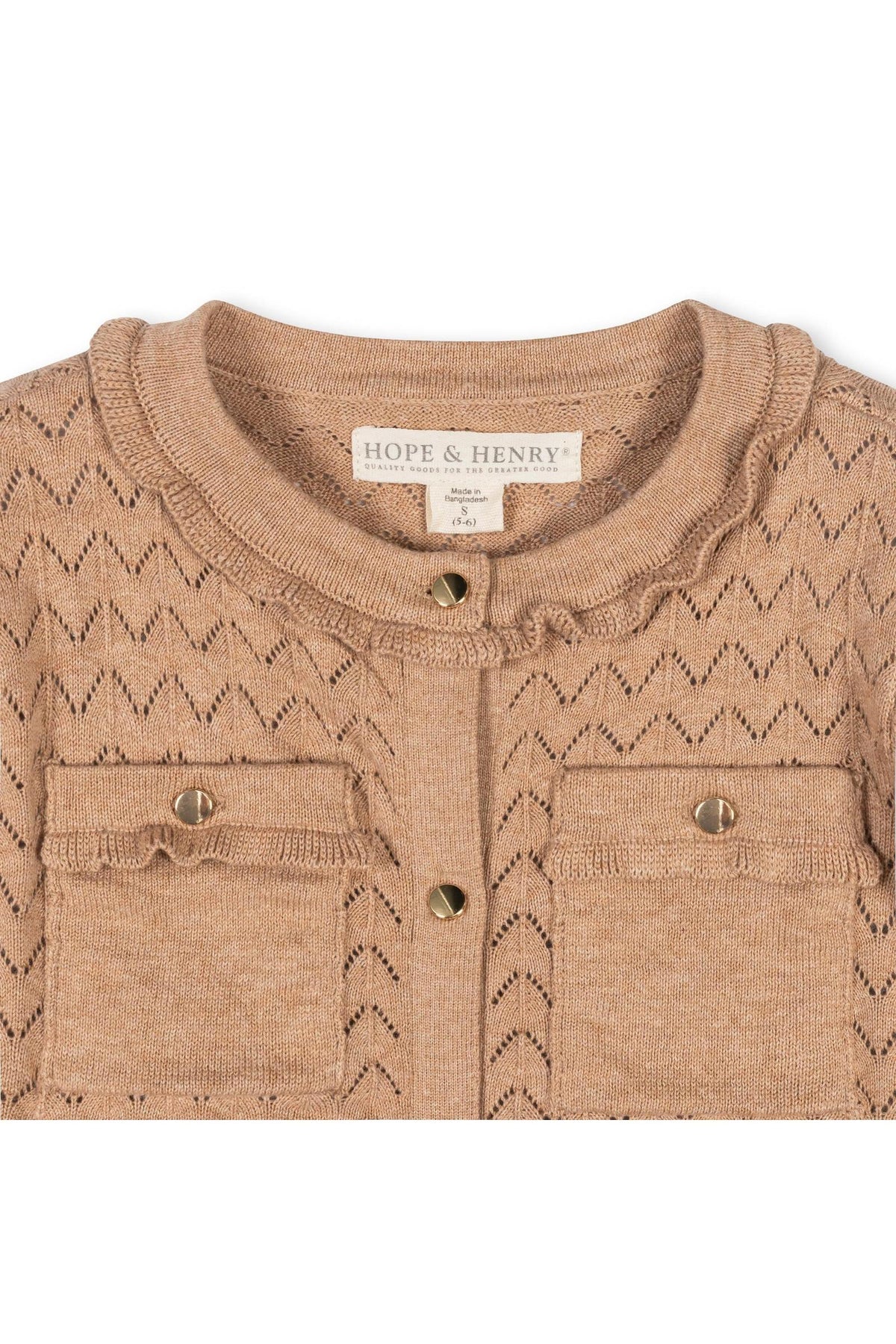 Close-up of a tan pointelle cardigan featuring a ruffle trim and two front pockets. Made from 100% organic cotton, this garment by Hope & Henry is perfect for toddlers and.